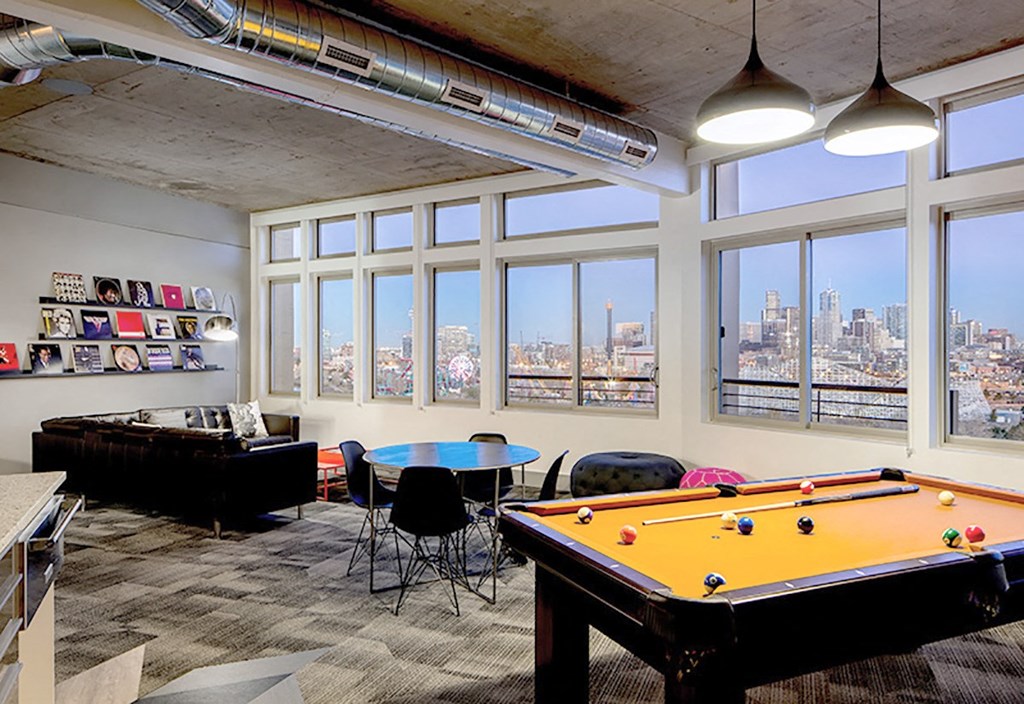 A room with a pool table and a view of the city.