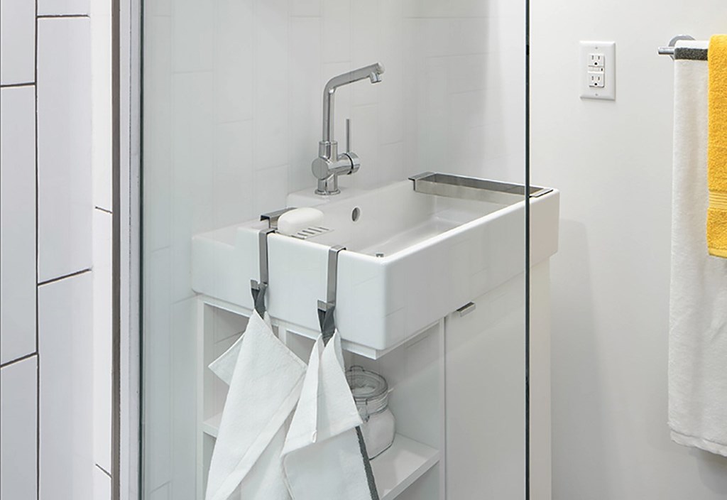 A white sink with a silver faucet and a white cabinet with a glass door.
