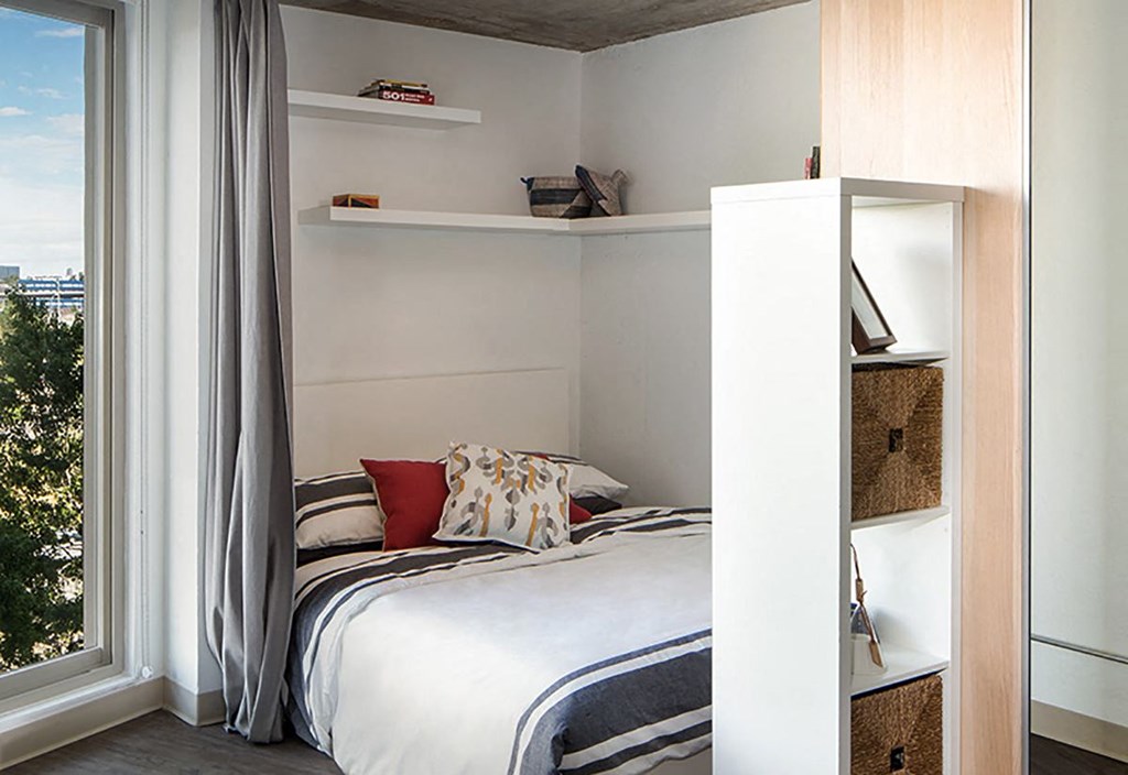 A bedroom with a bed, pillows, and a window with curtains.