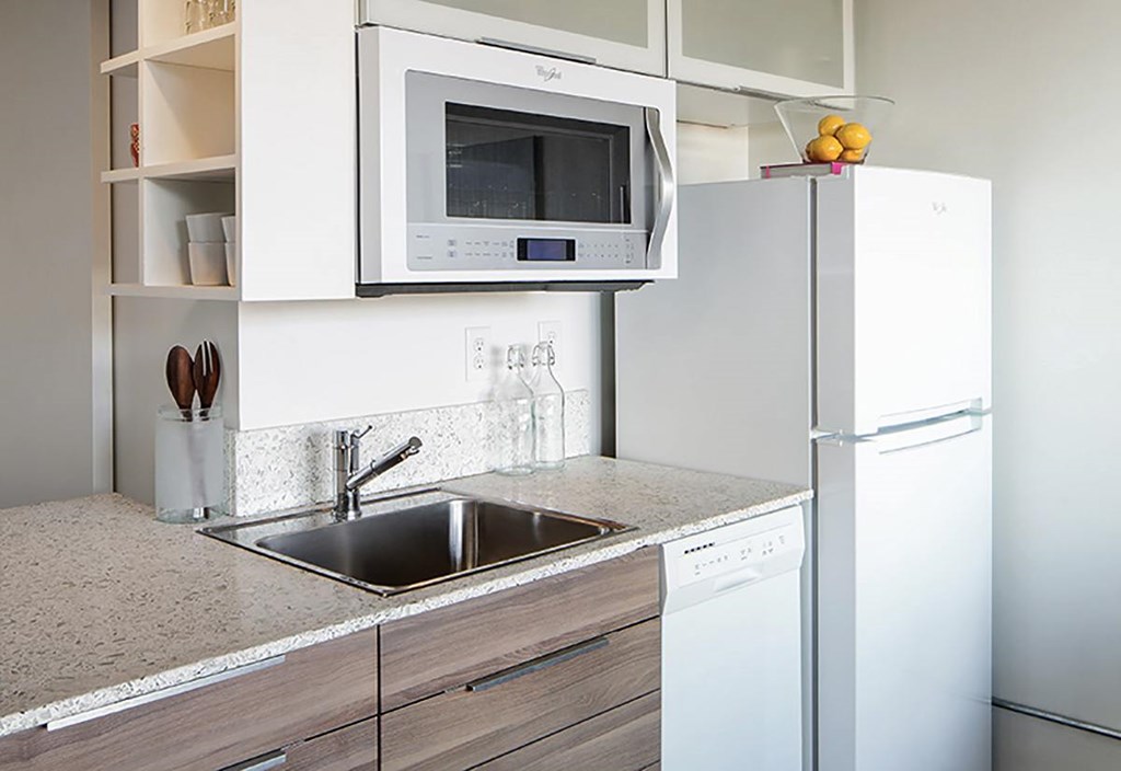 A modern kitchen with a white refrigerator, microwave, and dishwasher.