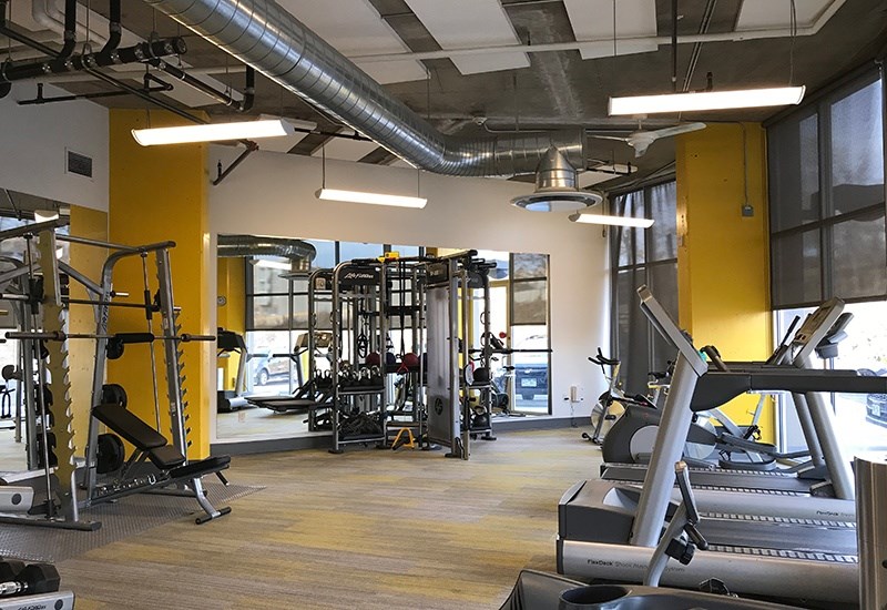 A gym with a variety of equipment including treadmills, weights, and exercise machines.
