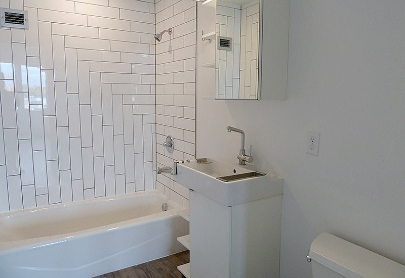 A white bathroom with a tub, sink and mirror.
