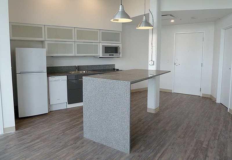 A kitchen with a white fridge and a grey island.
