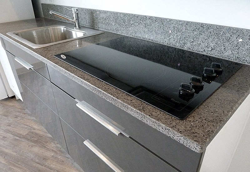A kitchen counter with a sink and a black cutting board.