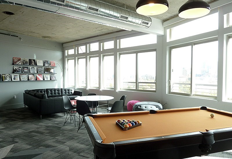 A pool table is in the middle of a room with a couch and chairs.
