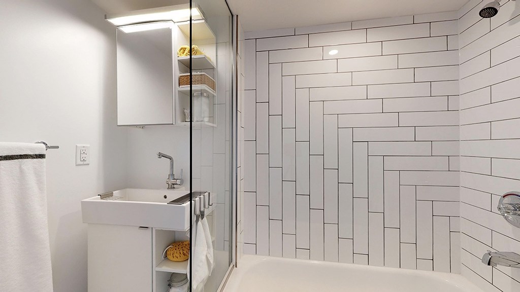 A white sink with a white cabinet and a white bathtub in a bathroom.