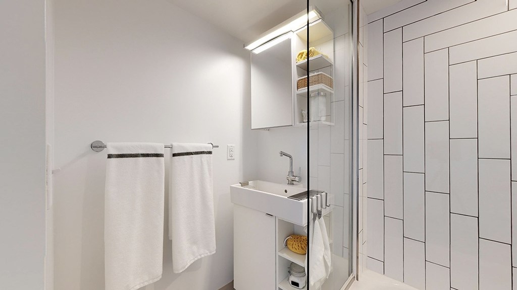 A white bathroom with a sink, mirror, and towel rack.