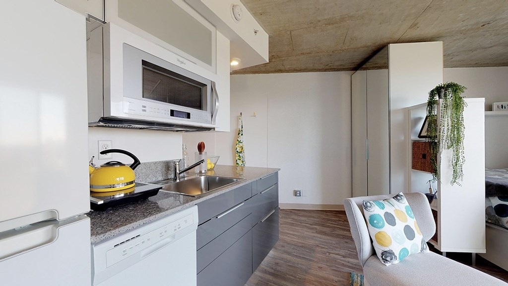 A modern kitchen with a white refrigerator, a yellow kettle, and a grey countertop.