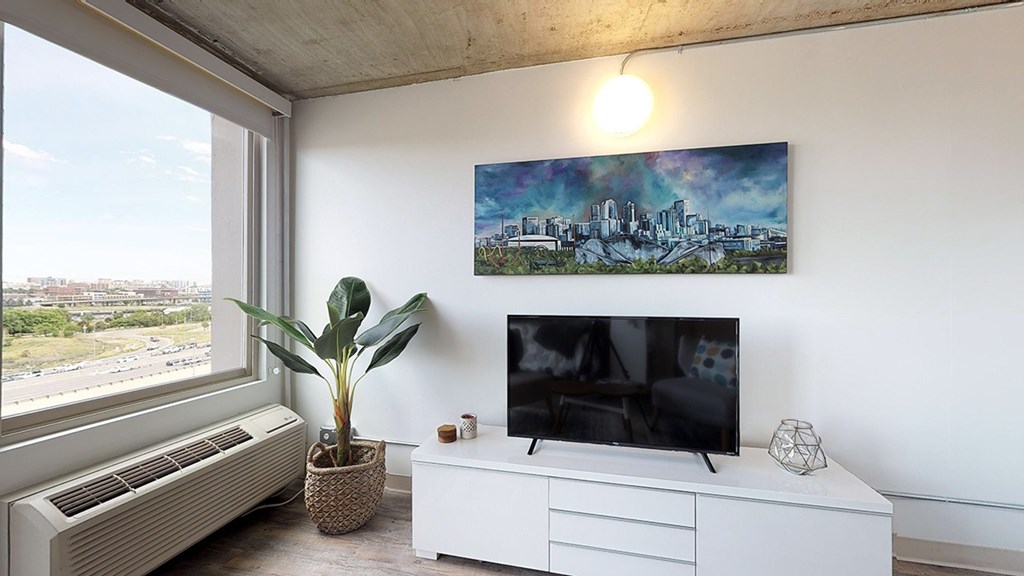 A room with a television, a plant, and a painting on the wall.