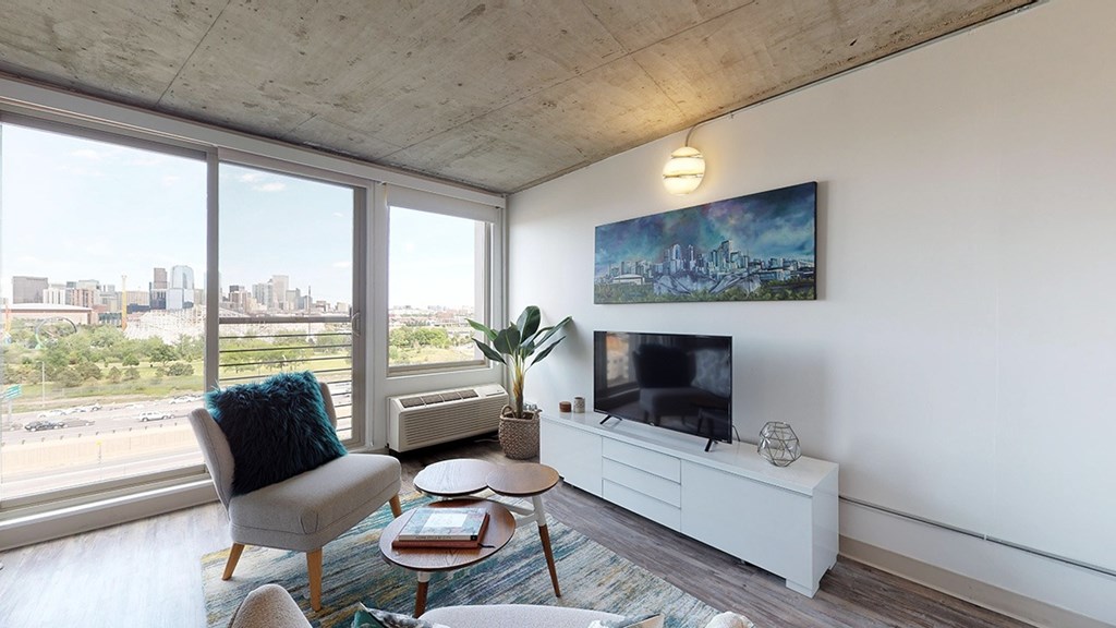 A living room with a chair, a table, a potted plant, and a painting on the wall.