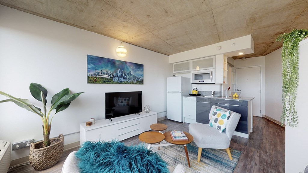 A living room with a blue rug and a painting on the wall.