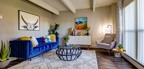 A living room with a blue couch and a painting on the wall.