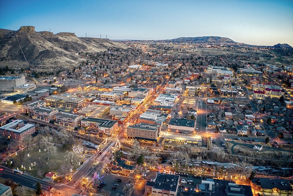 A cityscape at dusk with buildings illuminated and streets bustling with activity.