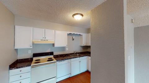 A kitchen with white cabinets and a black countertop.