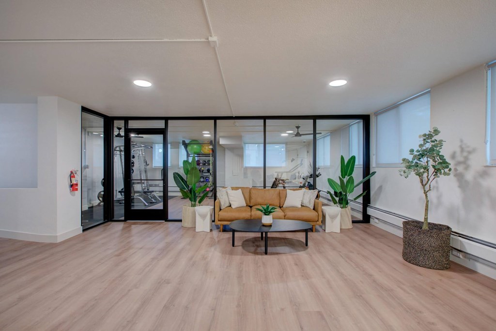 A modern living room with a wooden floor and a glass door leading to a balcony.