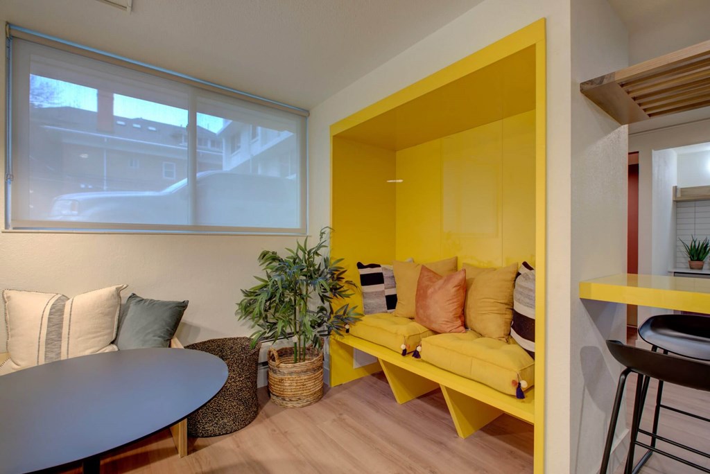 A yellow sofa with a plant on a table in a room.
