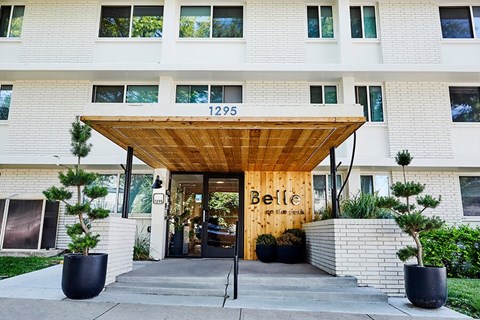 Building entrance with wooden canopy and landscaping at Belle on the Park Apartments, Denver, CO 80206
