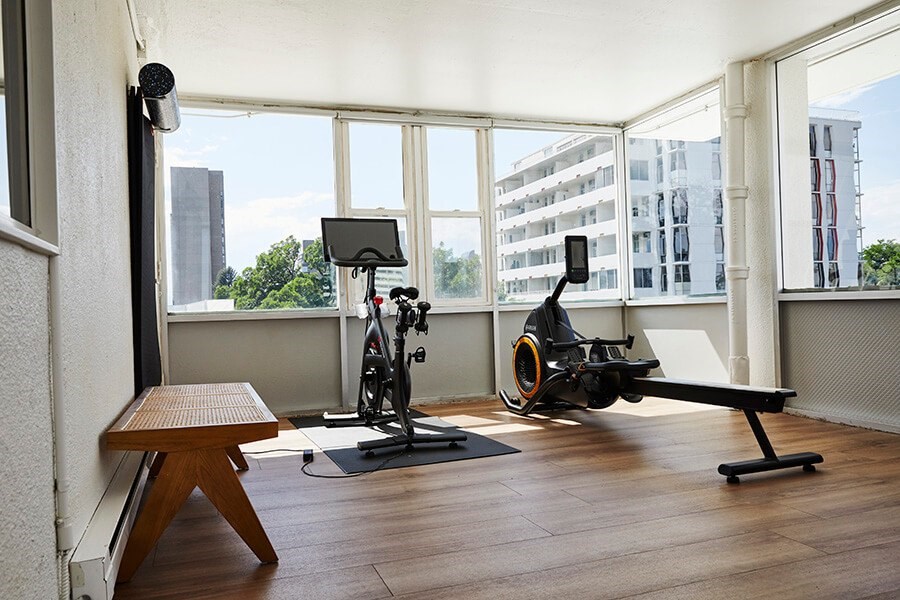 A light-filled room with a stationary bike and a rowing machine.