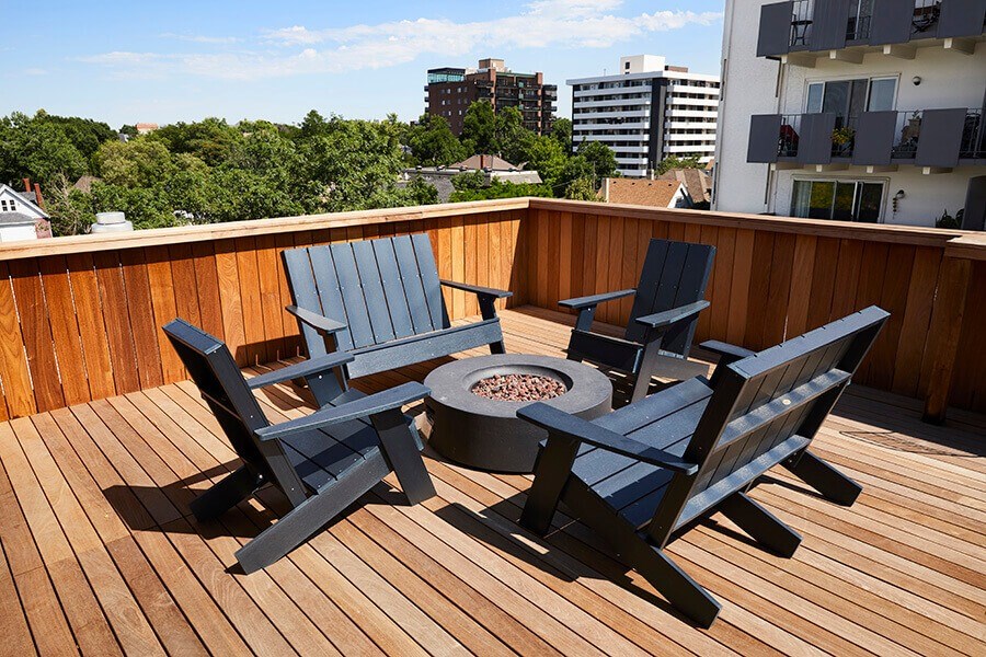 A wooden deck with a fire pit and chairs.