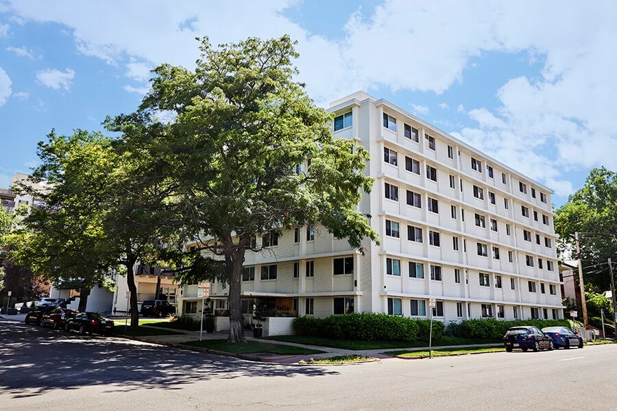 A white building with a tree in front of it.