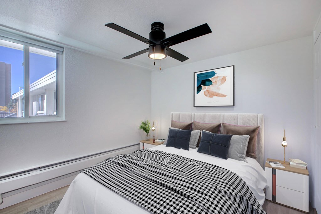 A bedroom with a bed, a ceiling fan, and a window.