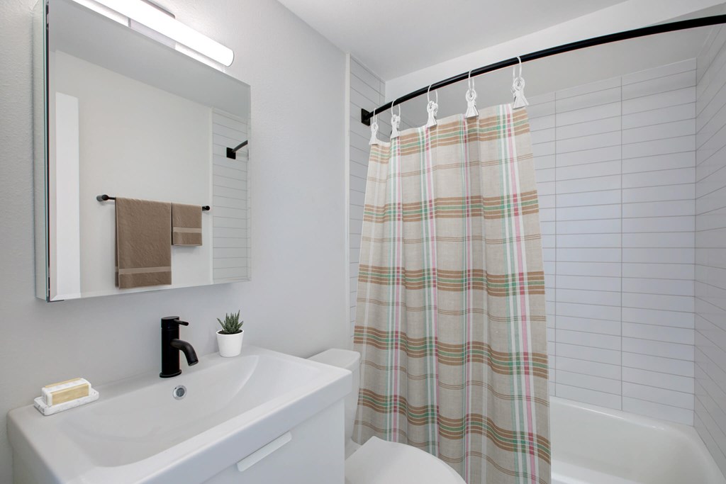 A bathroom with a white sink and a shower curtain.
