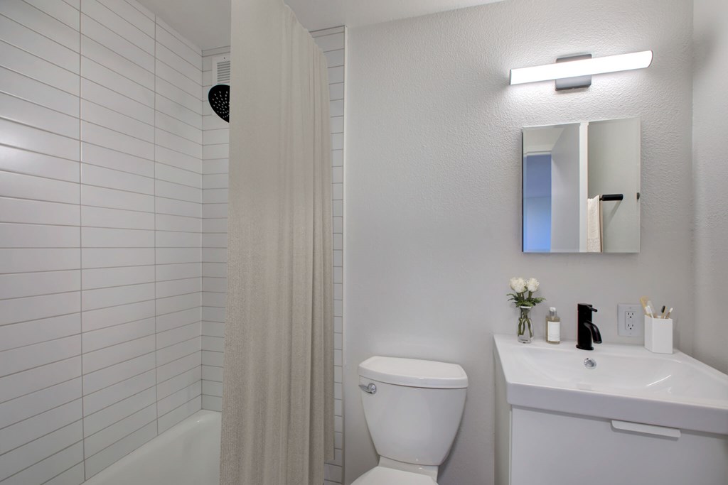 A white bathroom with a toilet, sink, and shower.