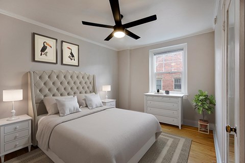 A bedroom with a large bed, a ceiling fan, and two framed pictures on the wall.