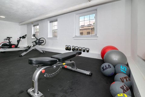 A gym room with a stationary bike, a rowing machine, and a set of dumbbells.