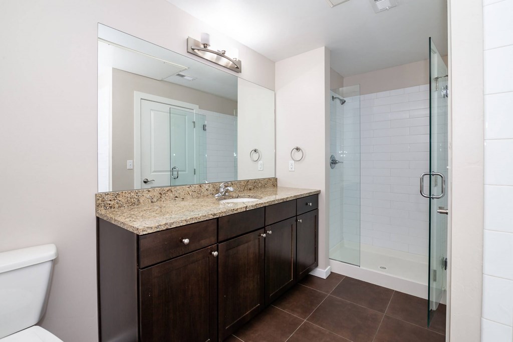 A bathroom with a sink, mirror, and shower.