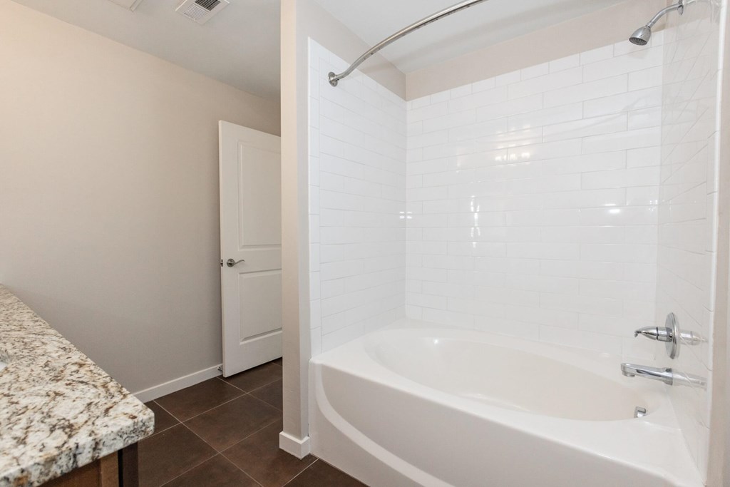 A white bathtub with a shower head and faucet.