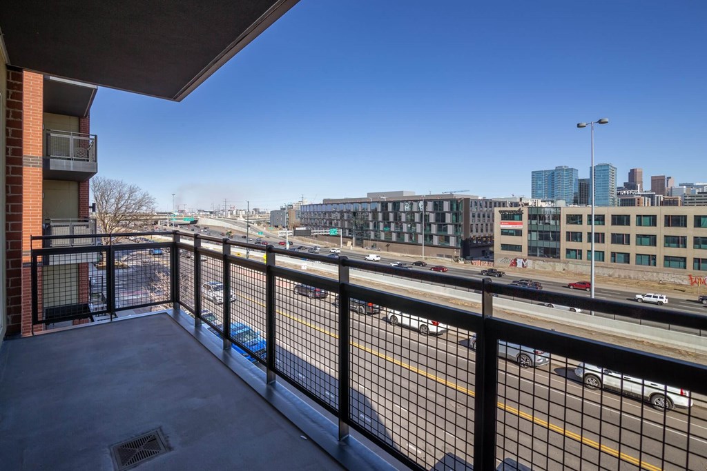 A balcony overlooks a busy highway with cars and buildings in the distance.
