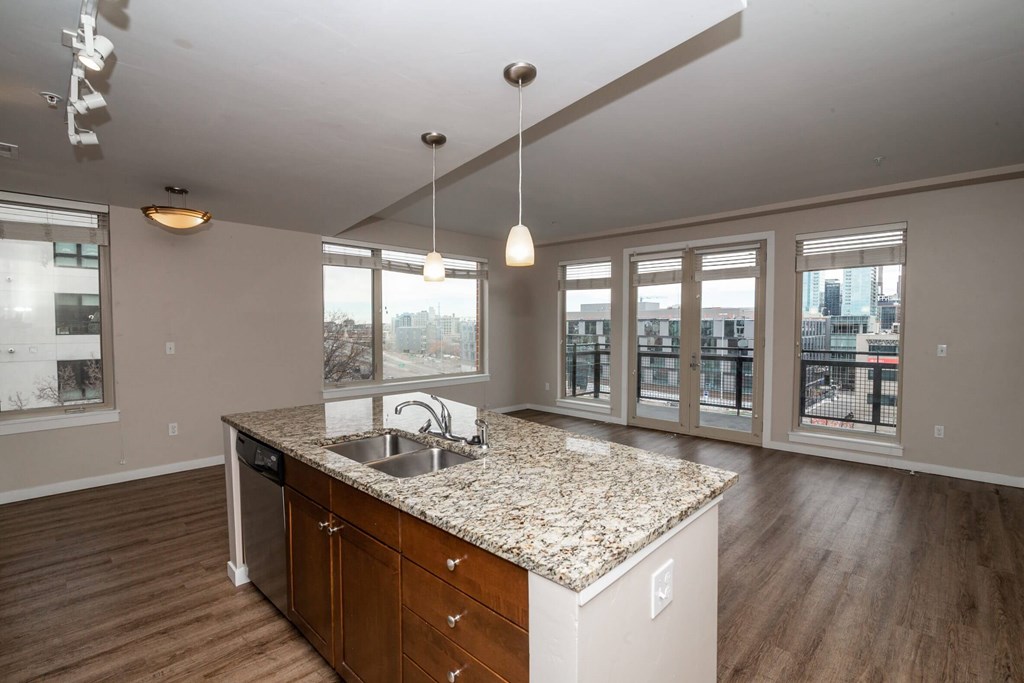 A kitchen with a granite countertop and wooden floors.