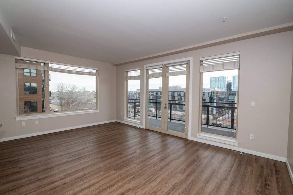 A room with wooden floors and large windows overlooking a cityscape.