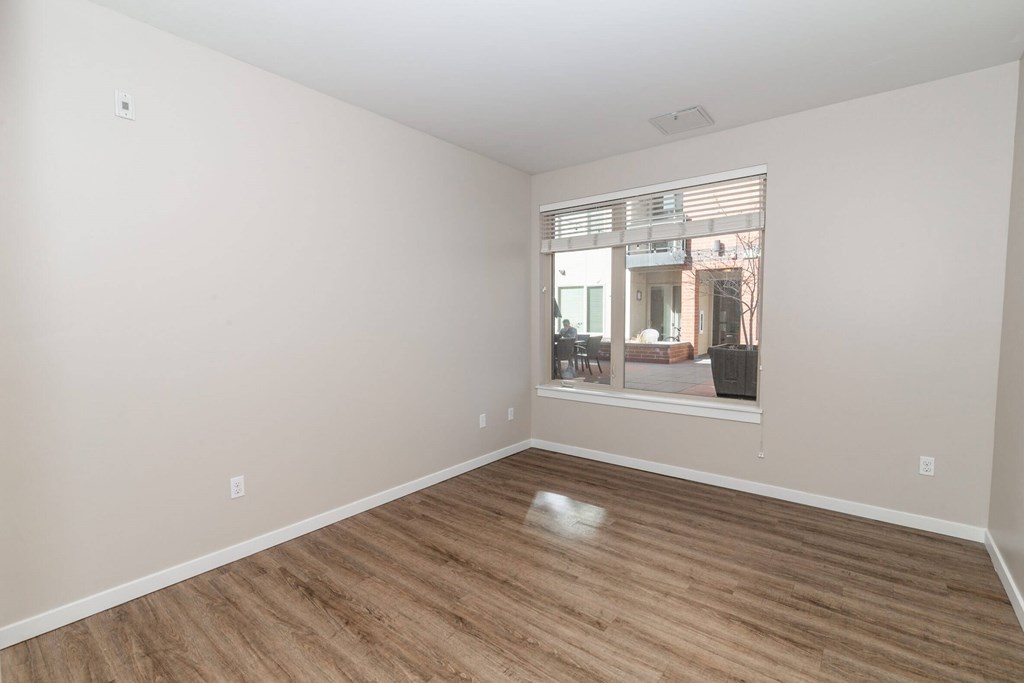 A room with wooden flooring and a window showing an outdoor scene.