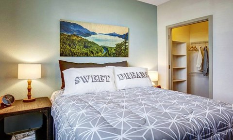 A bedroom with a bed, a lamp, and a painting on the wall.