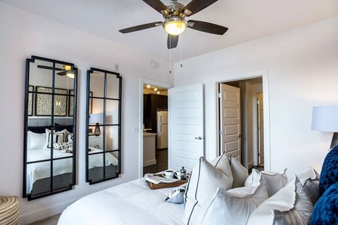 A bedroom with a white bed and a ceiling fan.