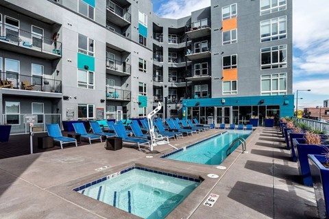 A large swimming pool with blue chairs and a building in the background.