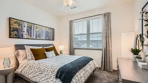 A bedroom with a large bed and a painting of trees above it.