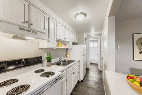 A modern kitchen with white cabinets and a stove top oven.