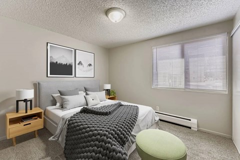 A bedroom with a bed, nightstand, and window.