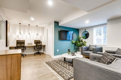 A modern living room with a grey couch and a blue accent wall.