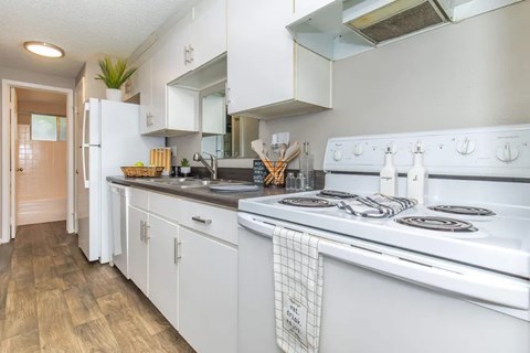 A white kitchen with a stove top oven and a refrigerator.
