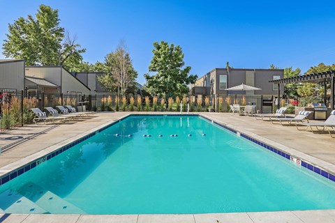 A large swimming pool with a blue tiled edge and a black fence surrounding it.