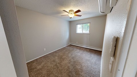 A room with a ceiling fan and carpeted floor.