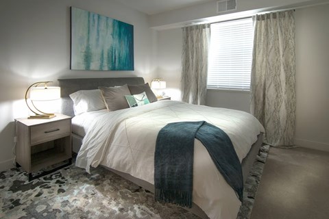 A bedroom with a large bed and a painting on the wall.