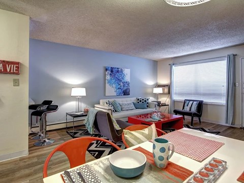 A living room with a white couch, a red chair, and a dining table with a bowl and a mug on it.