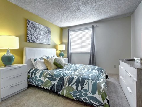 A bedroom with a bed, nightstands, and a painting on the wall.