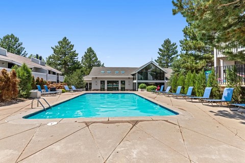 A swimming pool surrounded by lounge chairs and trees.