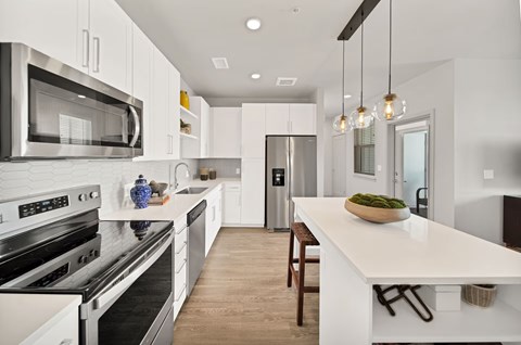 A modern kitchen with a white island and stainless steel appliances.